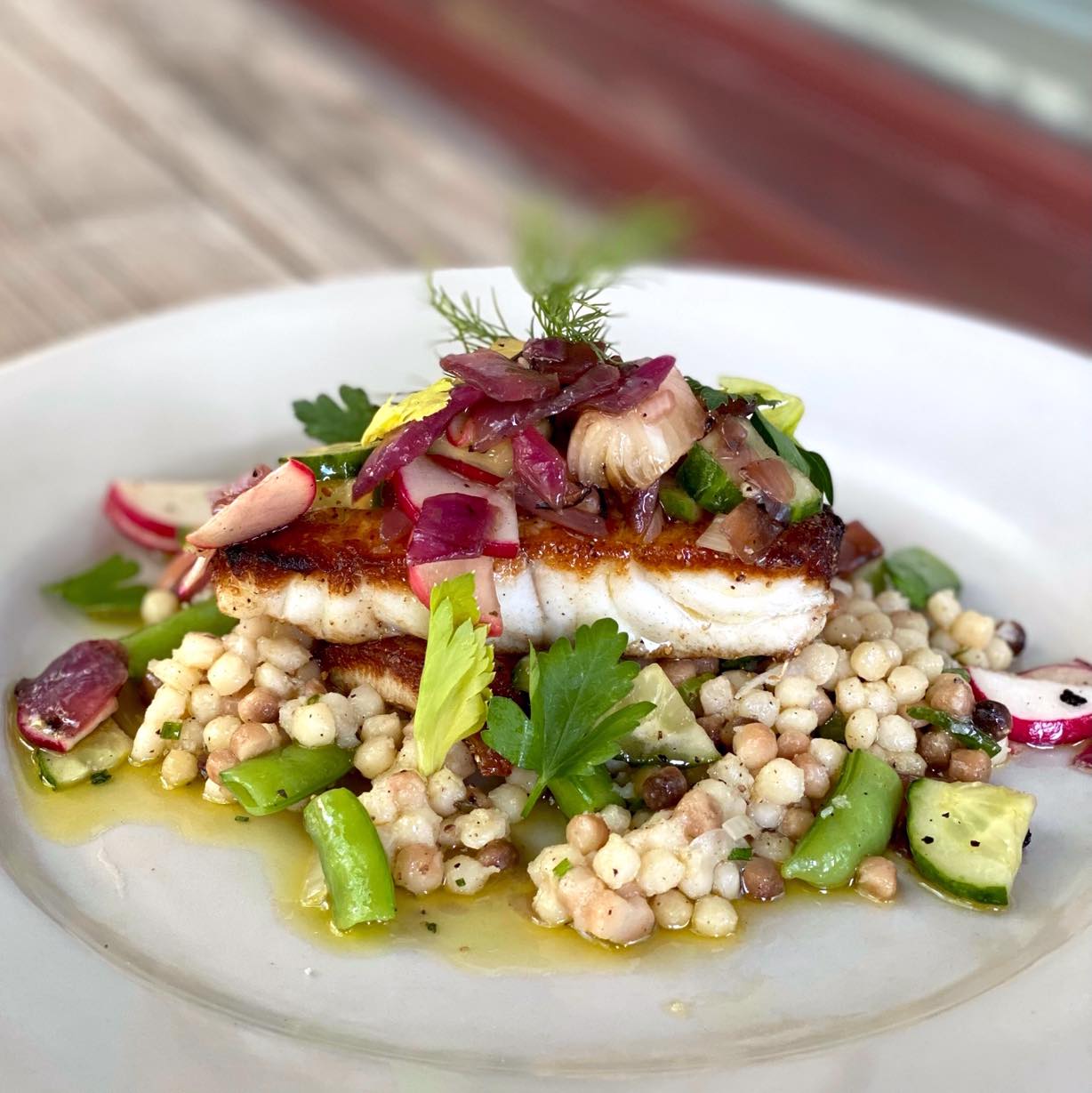 Pan-seared halibut on a bed of couscous with spring vegetables and cucumber relish at Chez Fonfon in Birmingham, Alabama.