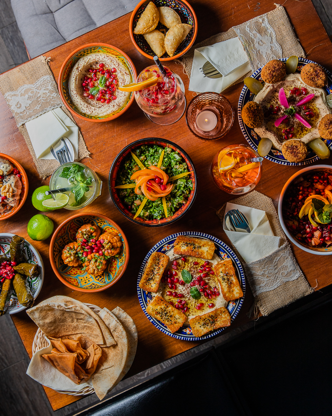 A variety of dishes including hummus, stuffed pastries, flatbread, and drinks.