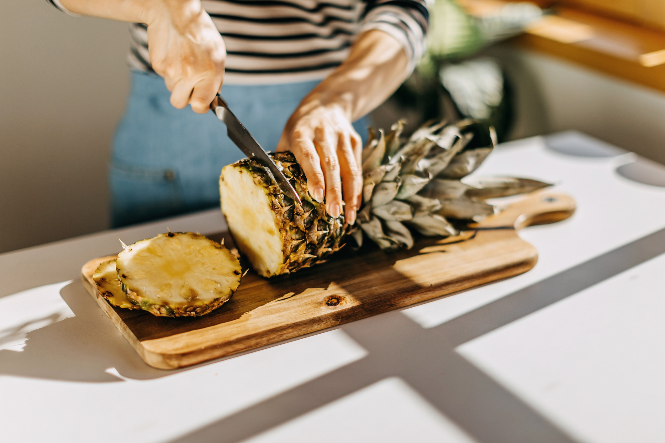 Woman cutting pineapple on countertop