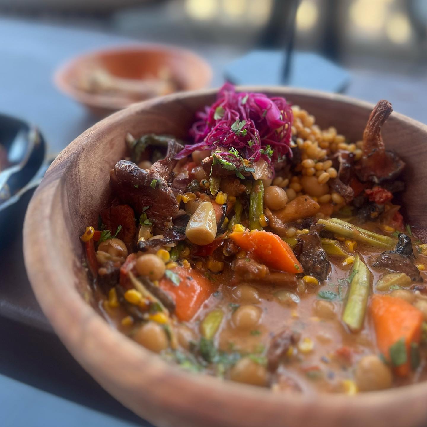 A wooden bowl filled with vegetables and grains.